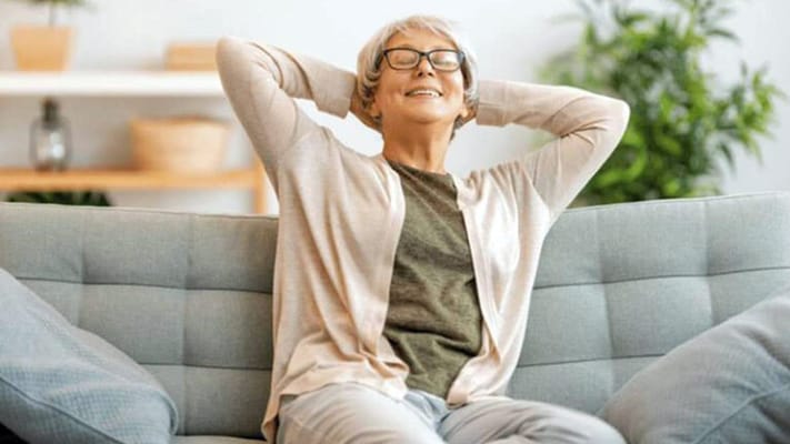 Resident relaxing on a couch in a sunny common area