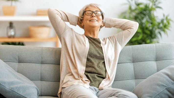 Resident relaxing on a couch in a sunny common area