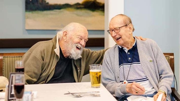 Two residents sharing a laugh in the dining area