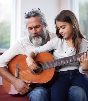A man playing guitar with a girl in a cozy room