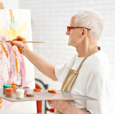 An elderly man painting on a canvas in an activity room