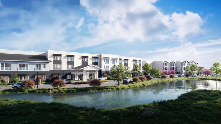 Exterior view of a senior living facility next to a pond