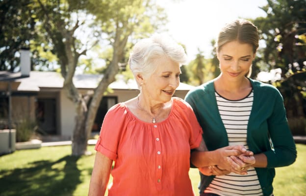 A resident and staff member walking in the garden