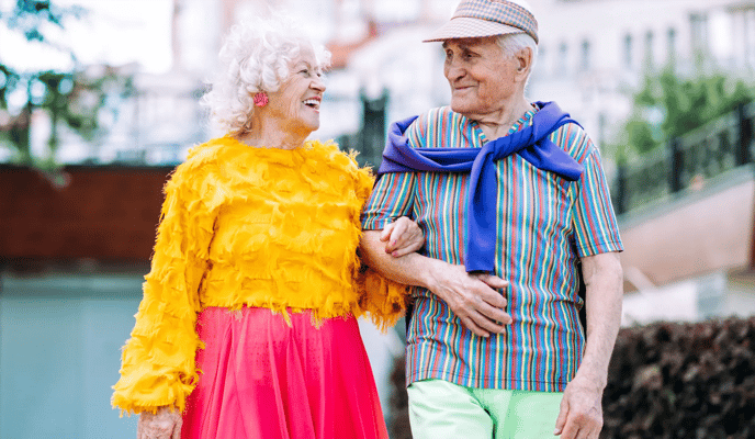 Elderly couple walking outdoors in colorful clothing