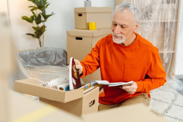 Senior man unpacking books from a box in a living space