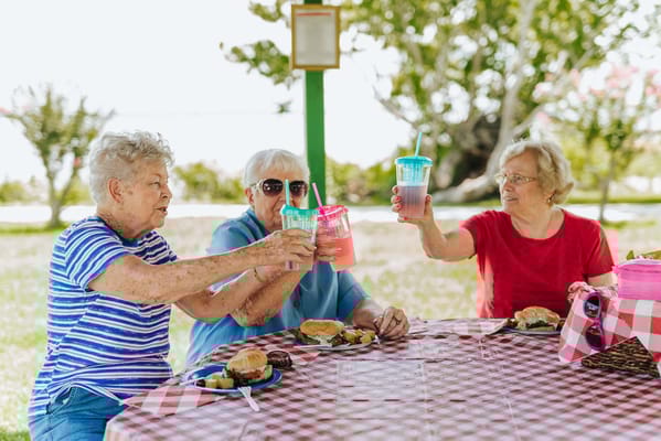 Three residents enjoying a meal and drinks outdoors