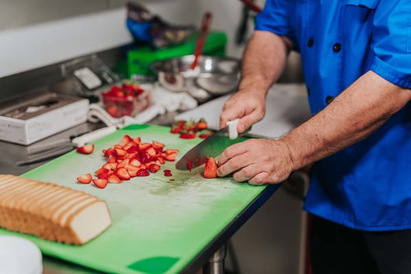Staff member preparing fresh strawberries in the kitchen