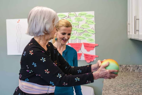 An elderly woman participating in a therapeutic activity with staff