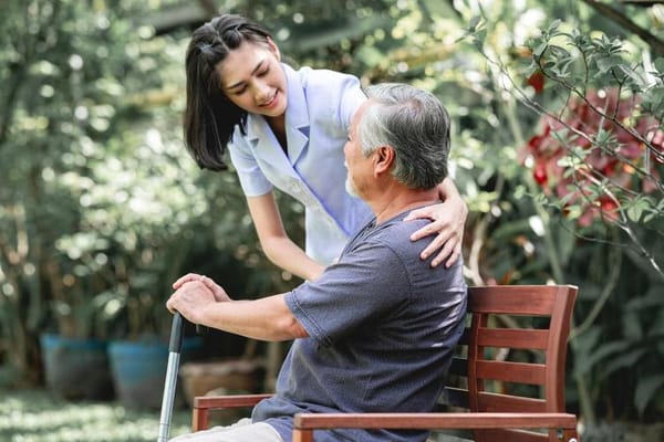 Caregiver assisting a resident in a garden setting