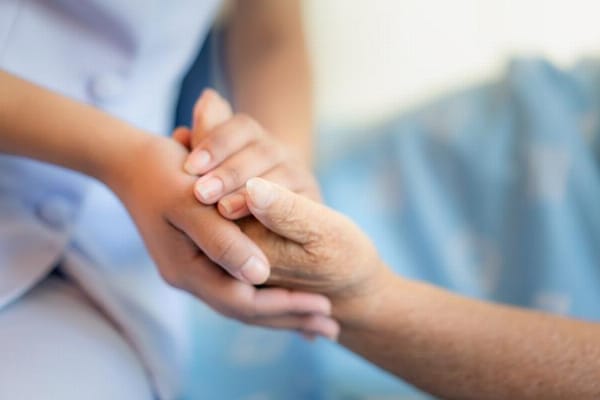 Caregiver holding a senior patient's hand