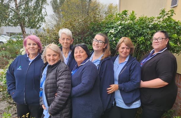 Staff members posing outside near greenery