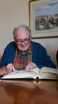 Senior resident reading a book at a table