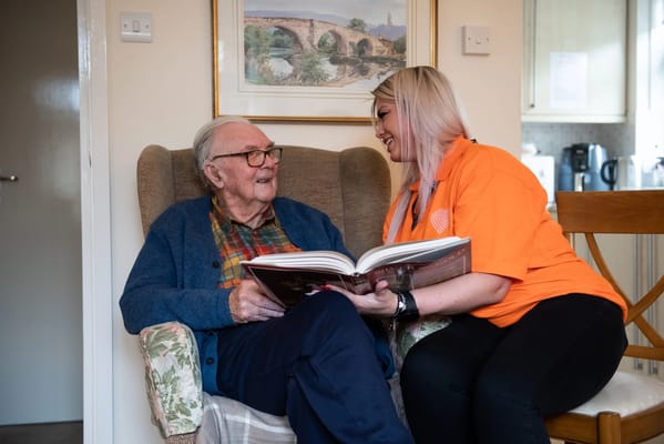 Care staff reading with an elderly resident