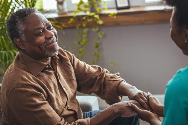 A smiling senior man holding hands with a caregiver
