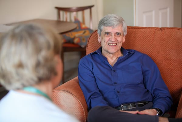 A resident smiling while sitting in a cozy chair