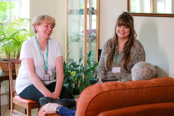 Two staff members engaging with a resident in a cozy common area