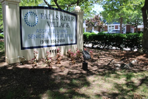 Sign for Falls River Village Assisted Living surrounded by greenery