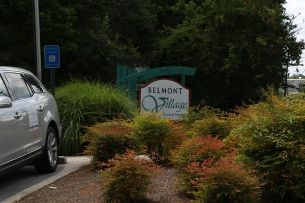 Sign at Belmont Village Senior Living Buckhead surrounded by greenery.