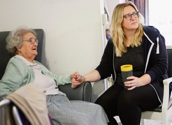 A resident and staff member sitting together in a cozy setting