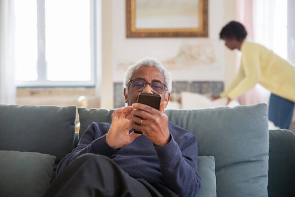 Senior man using a smartphone in a cozy living space