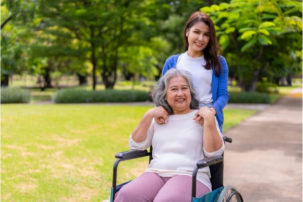 A caregiver helping a resident in a wheelchair outdoors
