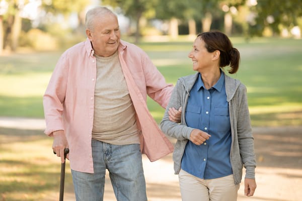 Senior man walking with staff member in a park
