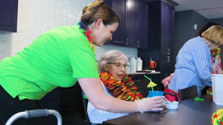 Resident enjoying a beverage with staff in an interior setting