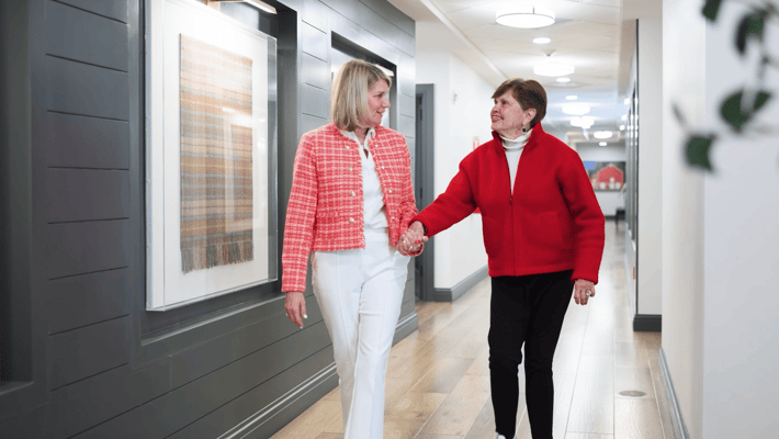 Two women walking together in a bright hallway