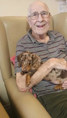 A resident holding a dog in a cozy setting