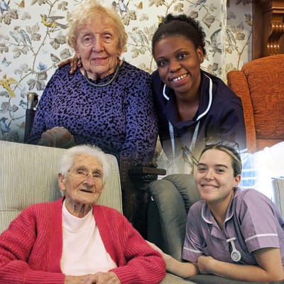 Residents and staff smiling together in a cozy common area
