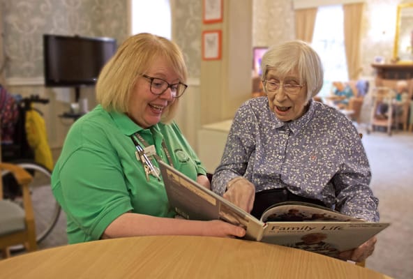 Staff member and resident reading together in a common area