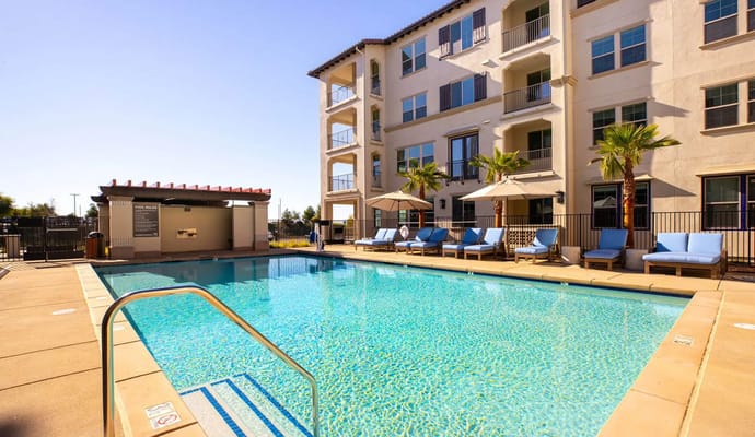 Outdoor pool area with lounge chairs and building in background