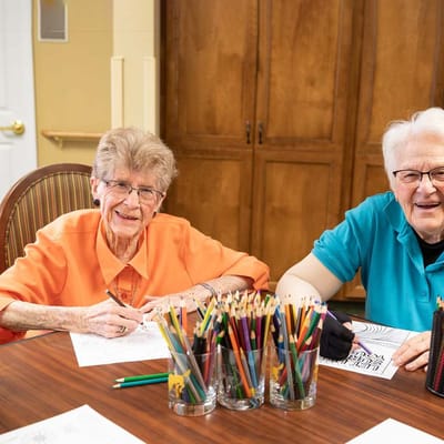 Two residents coloring together in an activity room