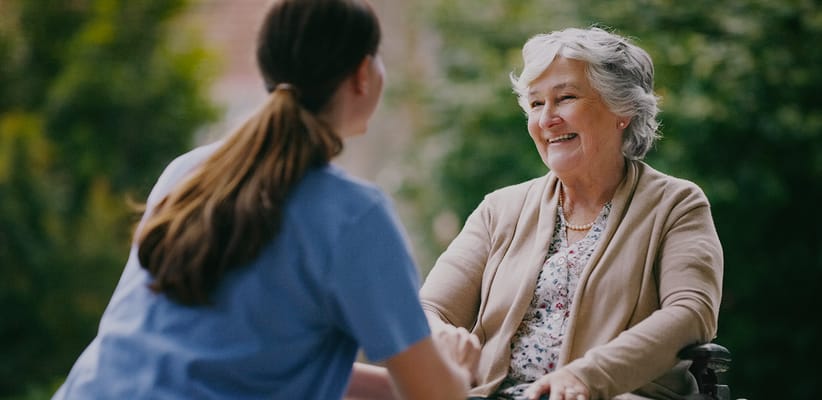 A caregiver talking with a smiling resident in a garden