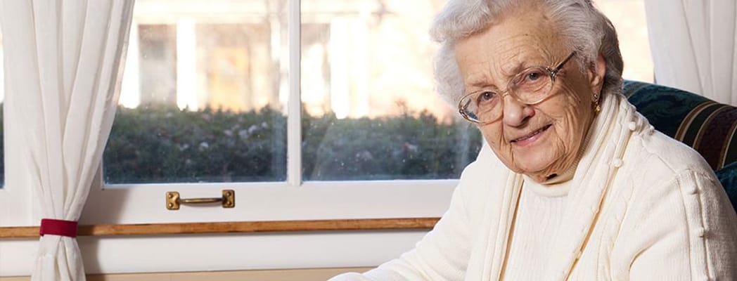 An elderly woman smiling in a cozy interior setting