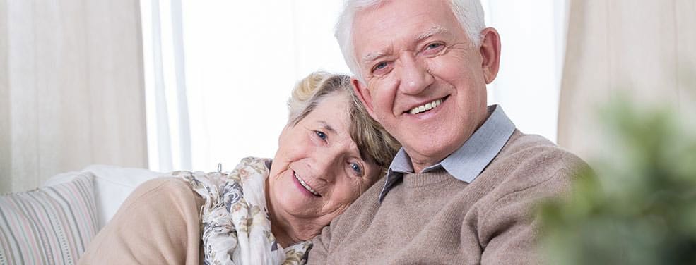 Senior couple smiling together on a couch