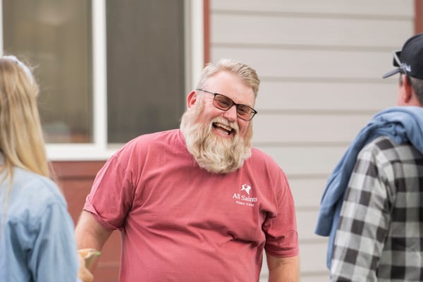 A smiling man wearing a facility shirt interacting outdoors
