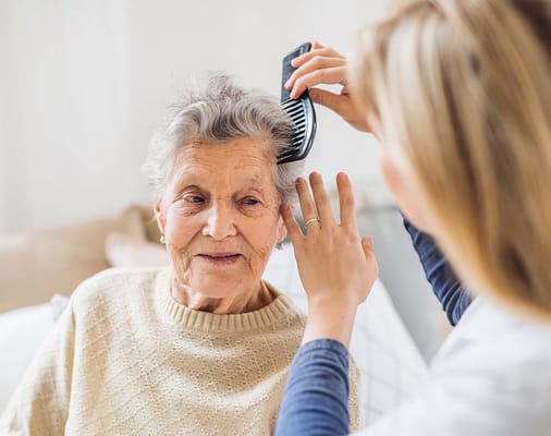 Caregiver styling an elderly woman's hair in a cozy setting
