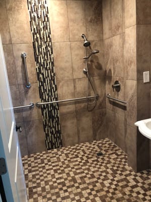 Accessible shower stall with grab bars in a tiled bathroom