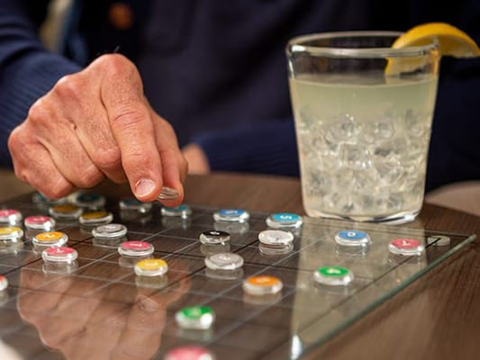 A resident playing a board game with a drink