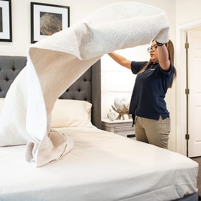 Staff member making a bed in a bright room