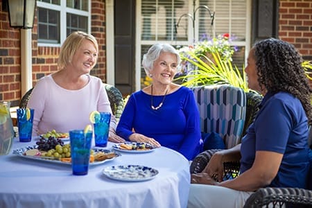 Residents enjoying a meal outside with staff