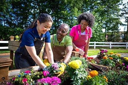 Residents and staff gardening together in a vibrant outdoor area