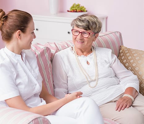 A caregiver and a resident sitting together in a cozy indoor setting.