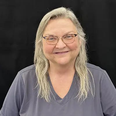 Staff member smiling in a gray uniform