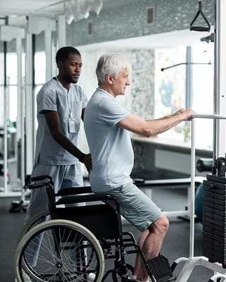 Resident using gym equipment with staff assistance