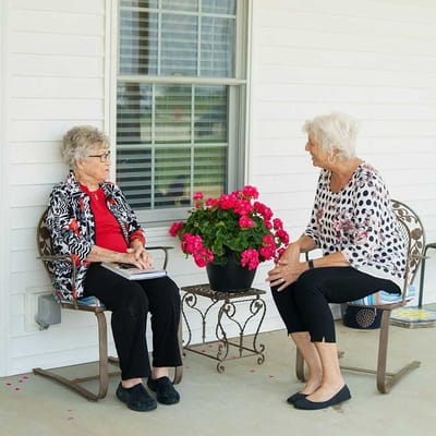 Two senior women enjoying a conversation on a porch