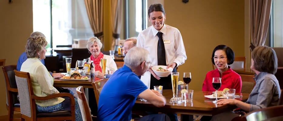 Residents enjoying a meal in the dining room with staff assistance