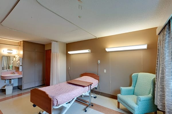 A shared resident room with two beds and a chair