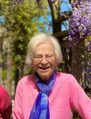 A smiling resident in a garden with flowers